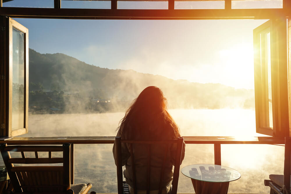 a women sitting on a table looking through the window